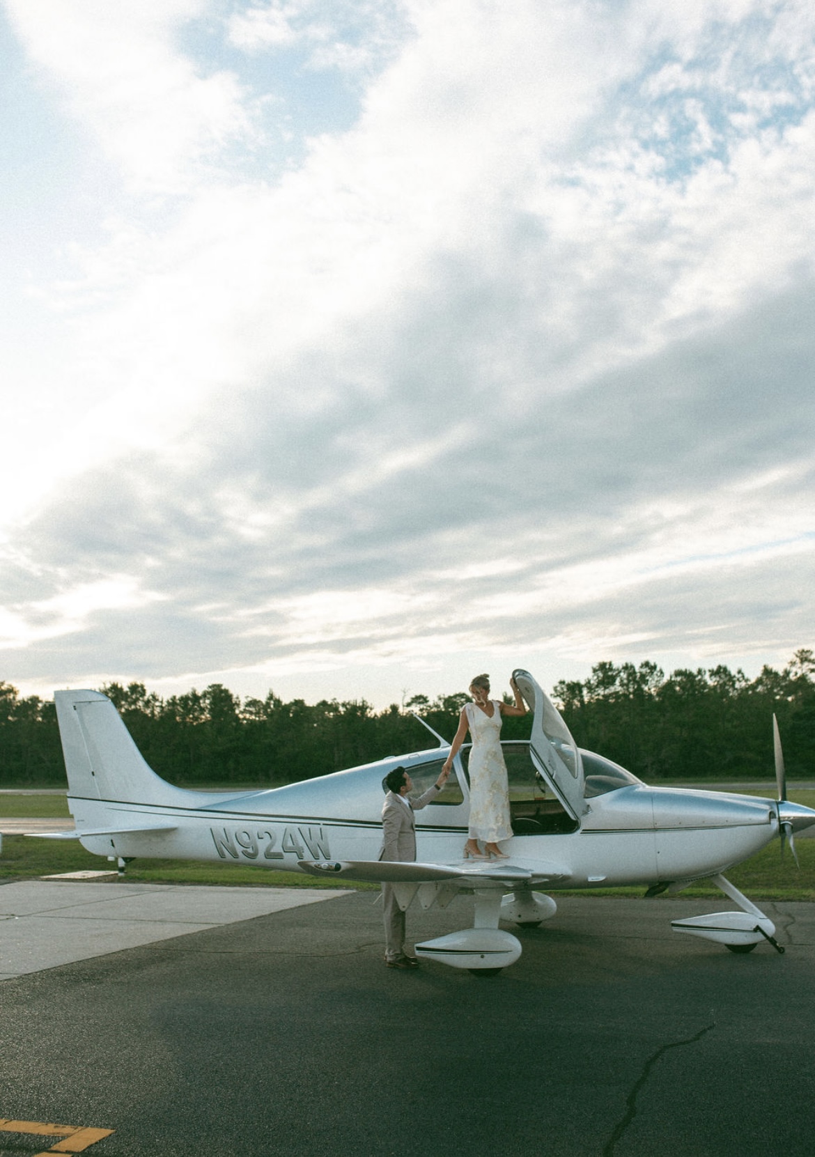 Couple taking proposal-style photos beside a Cirrus aircraft